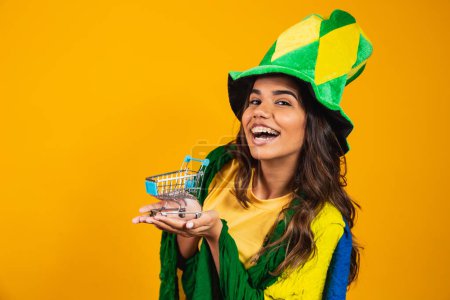 Photo for Football promotion. Woman holding a mini shopping cart in hands wearing brazilian clothes. - Royalty Free Image