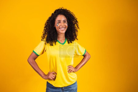 Foto de Apoyador brasileño. Aficionada brasileña celebrando en el fútbol o partido de fútbol sobre fondo amarillo. Brasil colores. - Imagen libre de derechos
