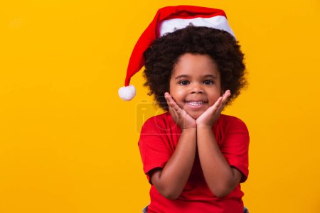 Photo for Adorable little afro girl in red t-shirt and Santa hat dressed for christmas with space for text - Royalty Free Image