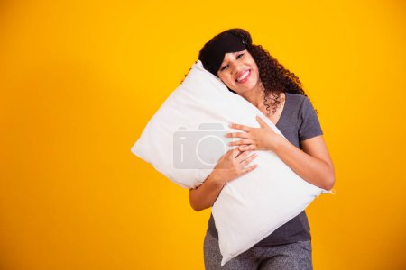 Foto de Foto de una chica afro abrazando almohada sobre fondo amarillo. Primer plano de la joven sosteniendo una almohada en sus manos. concepto de sueño - Imagen libre de derechos