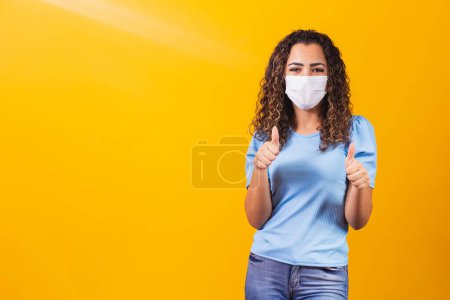 Photo for Young black model wearing protective mask with thumb up - Royalty Free Image