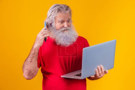 Téléchargez les photos : Vieil homme sur fond jaune faire un appel vidéo sur l'ordinateur portable. - en image libre de droit