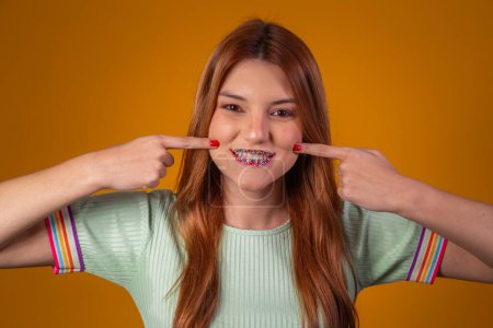 Foto de Mujer pelirroja joven con la boca con salpicaduras de colores como lápiz labial. Dulces labios jóvenes con salpicaduras - Imagen libre de derechos