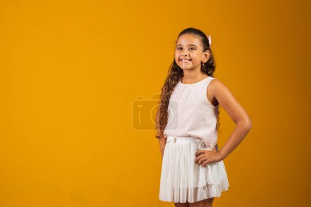 Téléchargez les photos : Adorable enfant fille avec de longs cheveux ondulés souriant à la caméra heureux - en image libre de droit