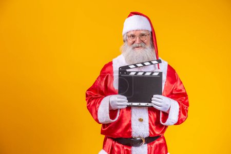 Téléchargez les photos : Il est temps d'agir. Joyeux père Noël âgé posant avec un clapperboard. - en image libre de droit