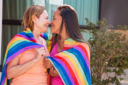 Téléchargez les photos : Couple lesbien avec drapeau lgbt embrassant eskimo. Saint Valentin - en image libre de droit