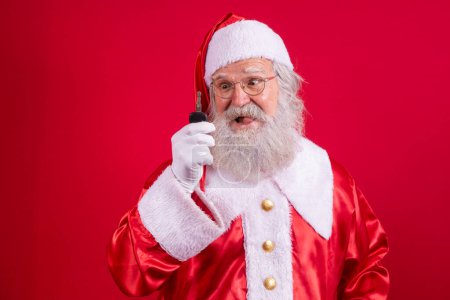 Photo for Santa Claus holding keys of a car on red background - Royalty Free Image