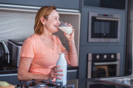 Téléchargez les photos : Femme âgée prenant un verre de lait le matin. - en image libre de droit
