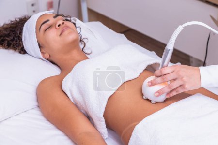 Foto de Inyección recortada de un dermatólogo profesional que realiza un procedimiento de elevación por radiofrecuencia en el estómago de una mujer. Cliente femenina recibiendo tratamiento de elevación de rf en su vientre en la clínica de cosmetología - Imagen libre de derechos