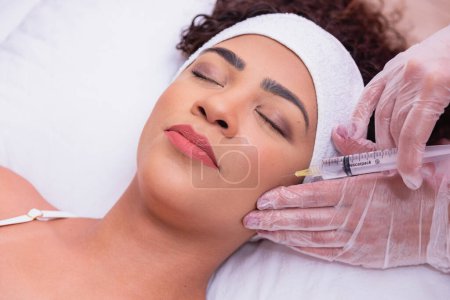 Photo for Pretty girl getting hyaluronic acid treatment. Attractive young woman is getting a rejuvenating facial injections. - Royalty Free Image