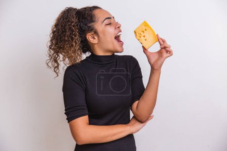 Photo for Young woman with a slice of cheese in her hand. woman eating parmesan cheese - Royalty Free Image
