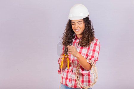 Photo for Female technique. Electrician woman on white background with space for text. Woman electrician holding wire and pliers. - Royalty Free Image