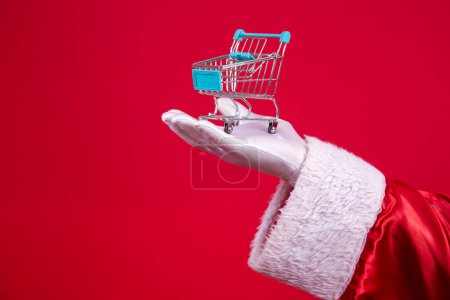 Téléchargez les photos : Père Noël et le supermarché, il montre un mini chariot. Noël et concept shopping
. - en image libre de droit