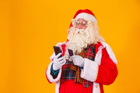 Foto de Santa Claus usando tarjeta de crédito para pagar las compras por internet - Imagen libre de derechos