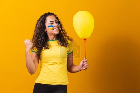 Téléchargez les photos : Ventilateur brésilien tenant un ballon jaune avec espace libre pour le texte. Brésil promotion du jeu - en image libre de droit