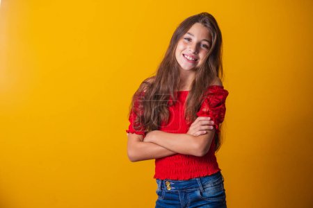 Photo for Adorable little pre teen girl on yellow background smiling with arms crossed. - Royalty Free Image