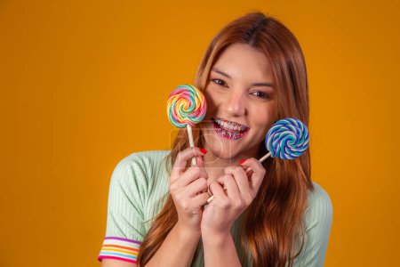 Photo for Brazilian redhead woman with two lollipops on yellow background smiling at camera - Royalty Free Image