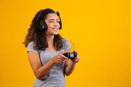 Téléchargez les photos : Femme excitée jouant jeu vidéo sur fond jaune. - en image libre de droit