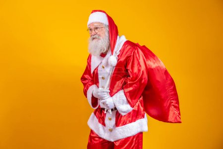 Photo for Real Santa Claus with a red background, wearing glasses, gloves and a hat looking side. - Royalty Free Image