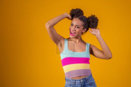 Photo for Beauty portrait of african american woman with afro hairstyle and glamour makeup. Brazilian woman. Mixed race. Curly hair. Hair style. Yellow background. Afro woman smiling at the camera - Royalty Free Image