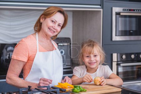 Foto de ¡Feliz día de la madre! Hija y mamá cocinando y divirtiéndose en la cocina en casa. Vacaciones familiares y unión
. - Imagen libre de derechos