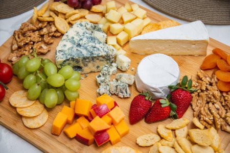 Cheese plate with variety of appetizers on table. Strawberry, apricot, grape and grain cheese dishes on the table