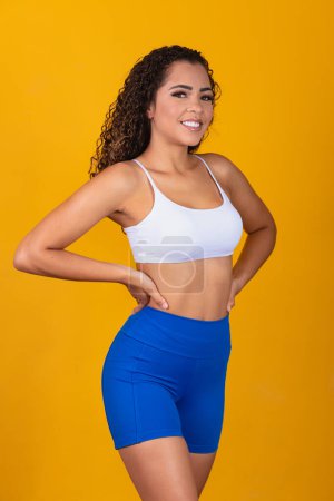 Photo for Beautiful young afro woman in fitness outfit smiling looking at camera with space for text. Vertical - Royalty Free Image