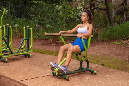 Foto de Mujer joven haciendo ejercicio en el parque. Mujer joven haciendo ejercicio de musculación de pecho y espalda. - Imagen libre de derechos