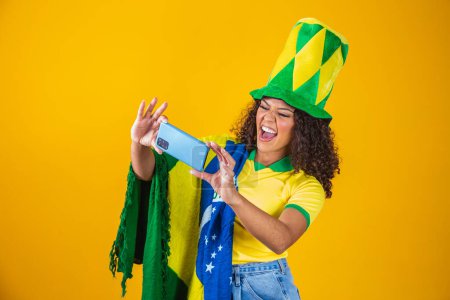 Téléchargez les photos : Supporteur de l'équipe brésilienne de football célébrant un objectif en regardant le smartphone - en image libre de droit
