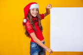 Happy little girl at Christmas with empty blank poster aside with space for text. Poster #655790676