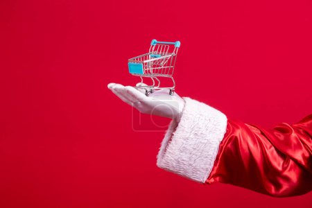 Photo for Santa Claus and the supermarket, he is showing a mini cart. Christmas and shopping concept. - Royalty Free Image
