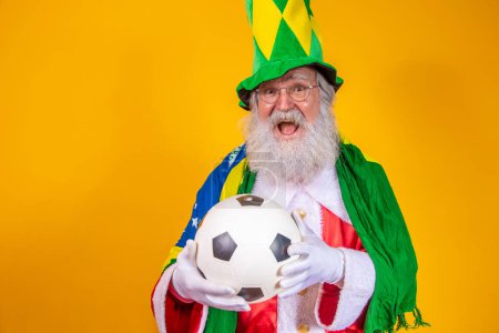 Photo for Santa Claus is a fan of Brazil. Santa Claus supporter of the Brazilian team. Sports championship. Santa Claus with the Brazilian flag and a ball. Football match. - Royalty Free Image