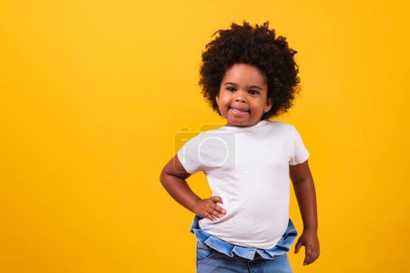 Téléchargez les photos : Concept d'enfance et de personnes - heureuse petite afro-américaine sur fond jaune. Petite fille noire avec des cheveux noirs de puissance souriant. - en image libre de droit