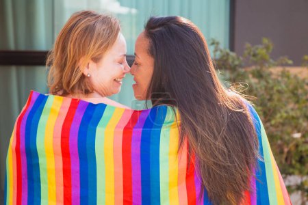 Photo for Lesbian couple with lgbt flag back to camera kissing eskimo. Valentines day - Royalty Free Image