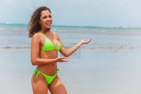 Téléchargez les photos : Belle femme afro brésilienne sur une plage à rio grande do norte, souriant, sentant la liberté et les vagues de la mer, profitant de ses vacances d'été avec un soleil merveilleux et la chaleur - en image libre de droit