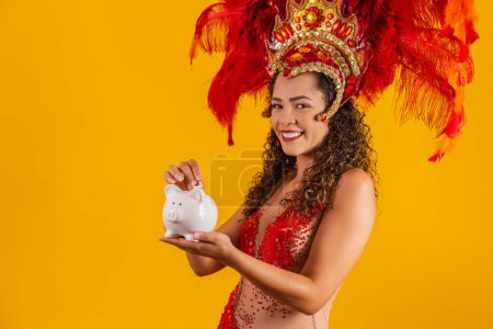 Photo for Carnival dancer woman holding a piggy bank in hands. Concept of saving for carnival - Royalty Free Image