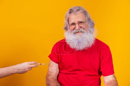 Photo for Santa Claus wearing face mask getting vaccinated with injection. elderly man vaccinating on free background for text. - Royalty Free Image