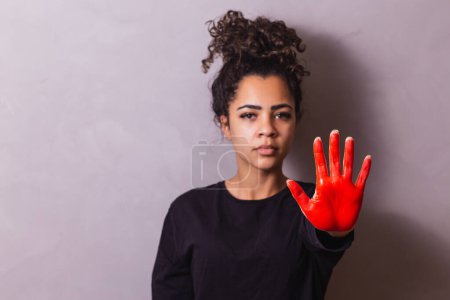 Foto de Afro mujer con la mano pintada de rojo con concepto de stop - Imagen libre de derechos