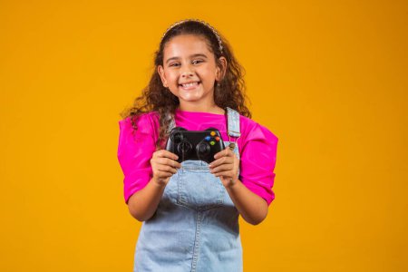 Photo for Little girl playing video game on yellow background. - Royalty Free Image