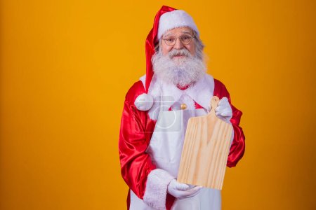 Téléchargez les photos : Père Noël vêtu d'un tablier contenant du carton de viande vide sur fond jaune. - en image libre de droit