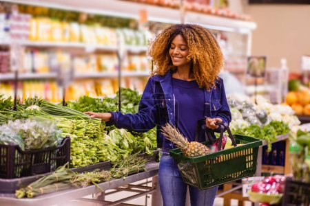 Foto de Afro joven comprando verduras y frutas en el supermercado. - Imagen libre de derechos