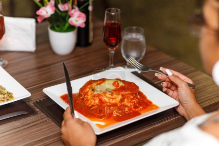 Photo for Woman eating a delicious dish of meat and noodles parmigiana. - Royalty Free Image