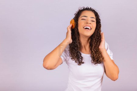 Foto de Mujer afro con auriculares escuchando música y bailando. Joven alegre con auriculares - Imagen libre de derechos