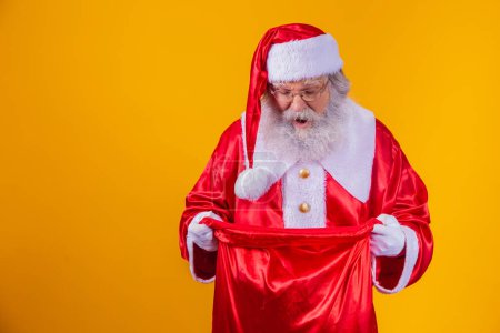 Téléchargez les photos : Curieux vrai Père Noël regardant dans le sac-cadeau - en image libre de droit