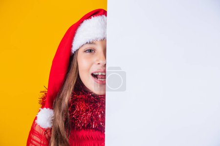 Téléchargez les photos : Bonne petite fille à Noël avec affiche vide vierge de côté avec de l'espace pour le texte. - en image libre de droit