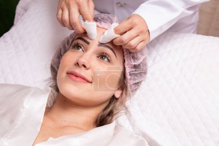 Téléchargez les photos : Femme faisant le nettoyage de la peau à la clinique d'esthéticienne. Nettoyage de la peau. Extraction des boutons du visage - en image libre de droit