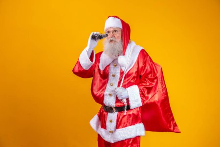 Foto de Estudio de Santa Claus mirando a través de prismáticos aislados sobre fondo amarillo - Imagen libre de derechos