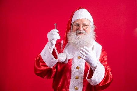 Photo for Santa Claus holding keys of new house or apartment on red background. - Royalty Free Image