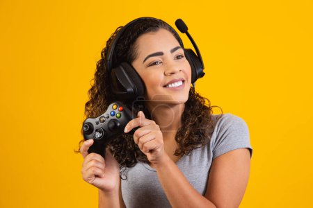 Photo for Excited woman playing video game on yellow background. - Royalty Free Image