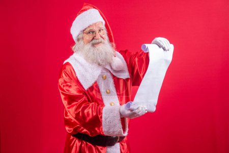 Téléchargez les photos : Portrait du Père Noël heureux lisant la lettre de Noël ou la liste de souhaits. - en image libre de droit